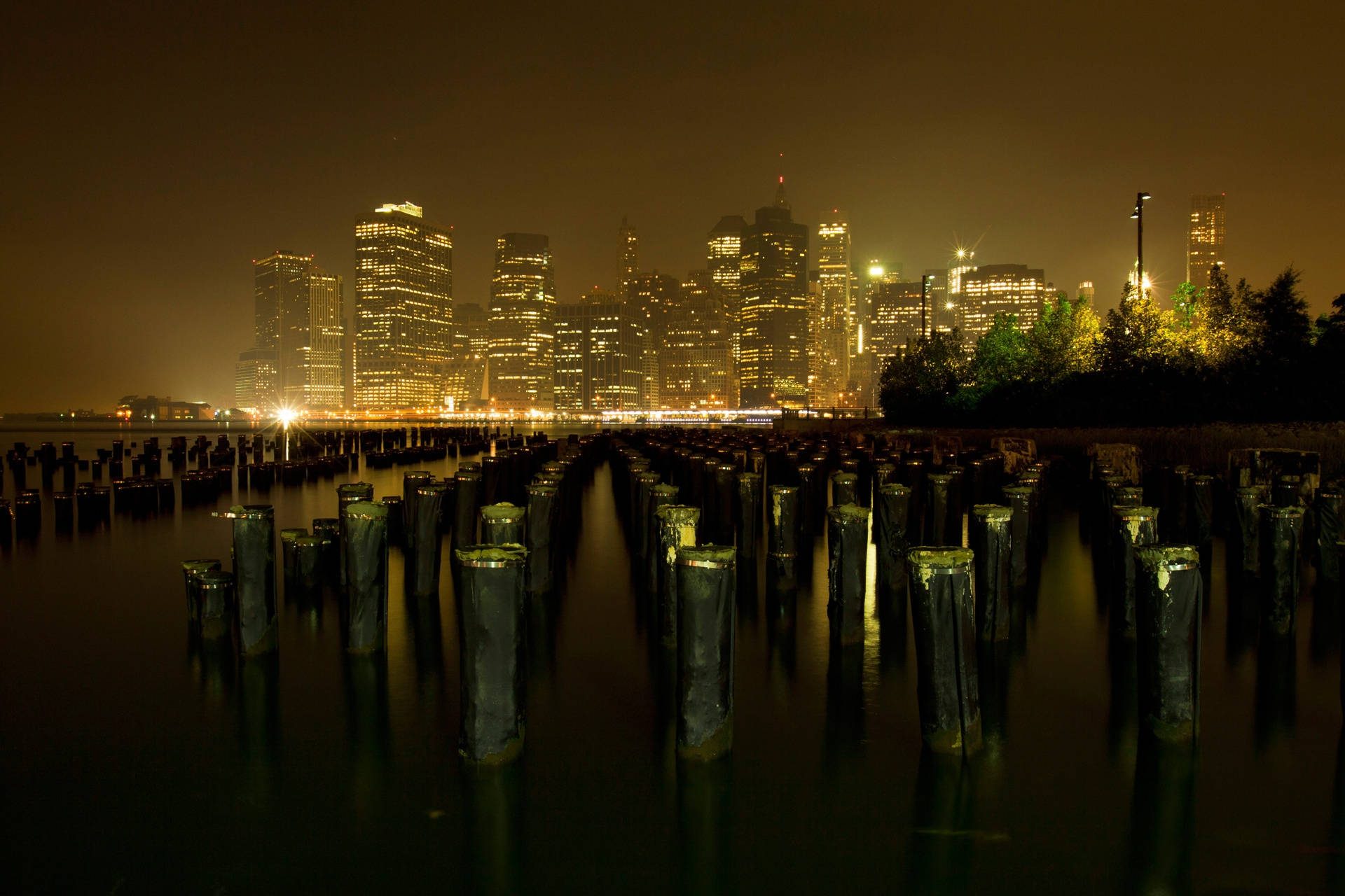 Take In The Views Of New York City At Night From Brooklyn Bridge Park Wallpaper