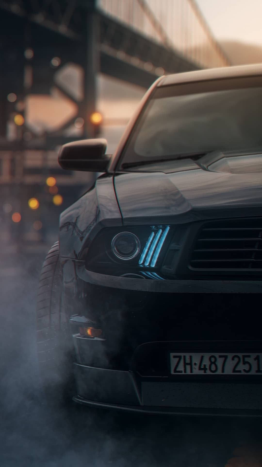 A Black Mustang Parked On A Street With Smoke Coming Out Of It Wallpaper