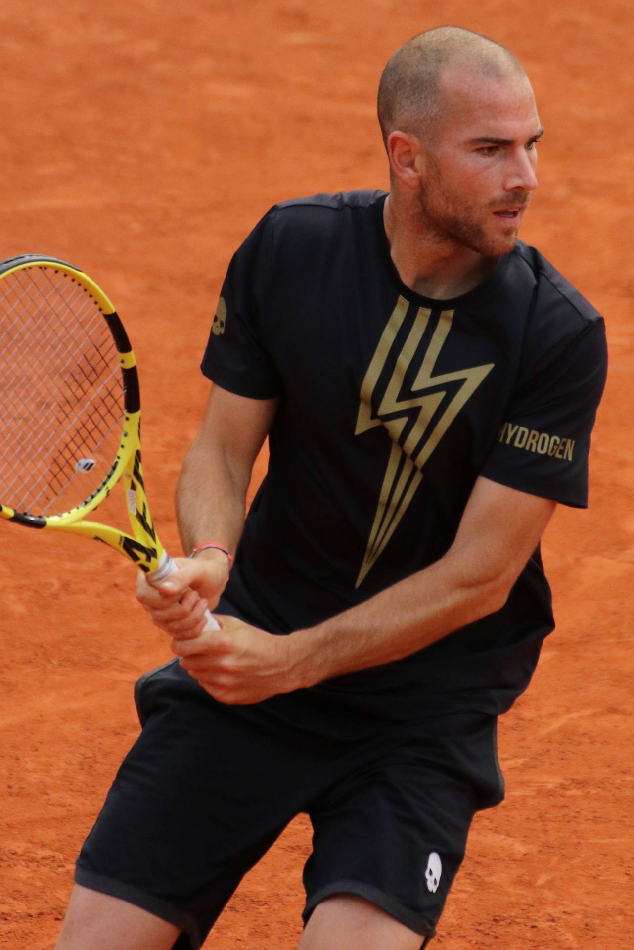 A Man Is Playing Tennis On A Clay Court Wallpaper