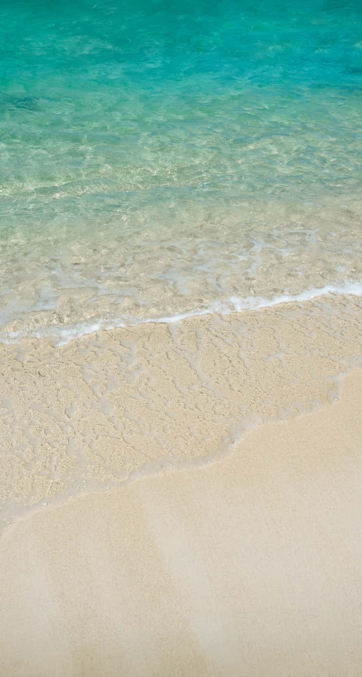 A Man Is Walking On A Sandy Beach With Water Wallpaper