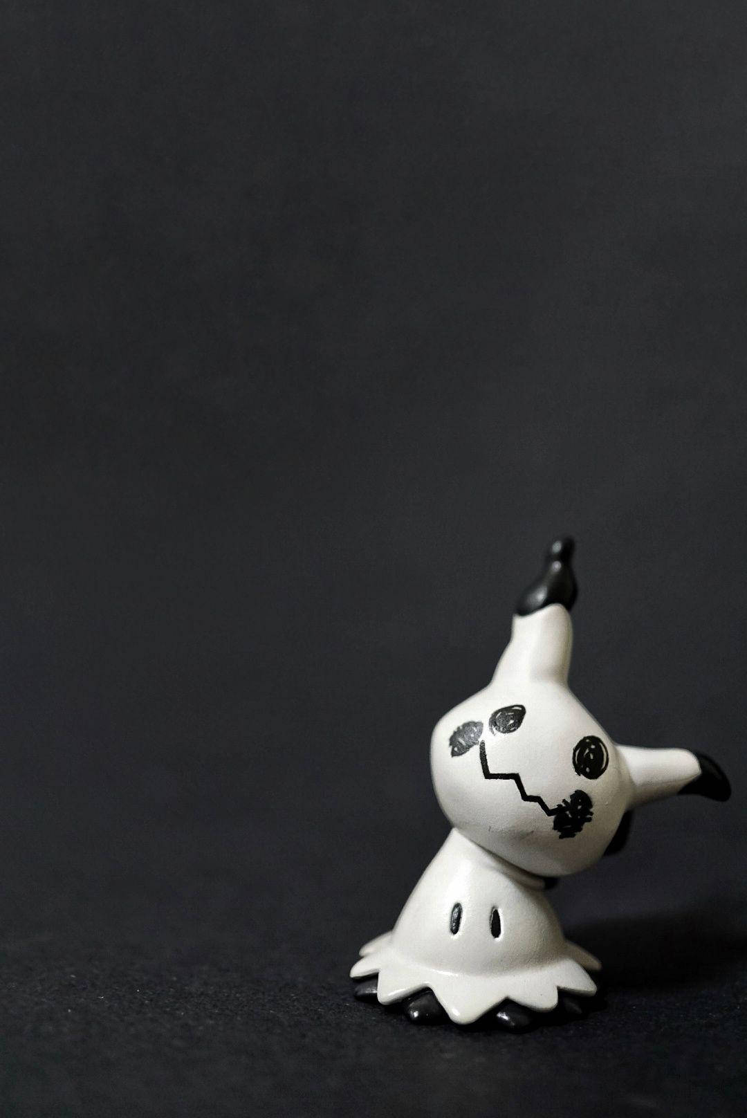 A Small Figurine Of A Ghost Sitting On A Black Surface Wallpaper