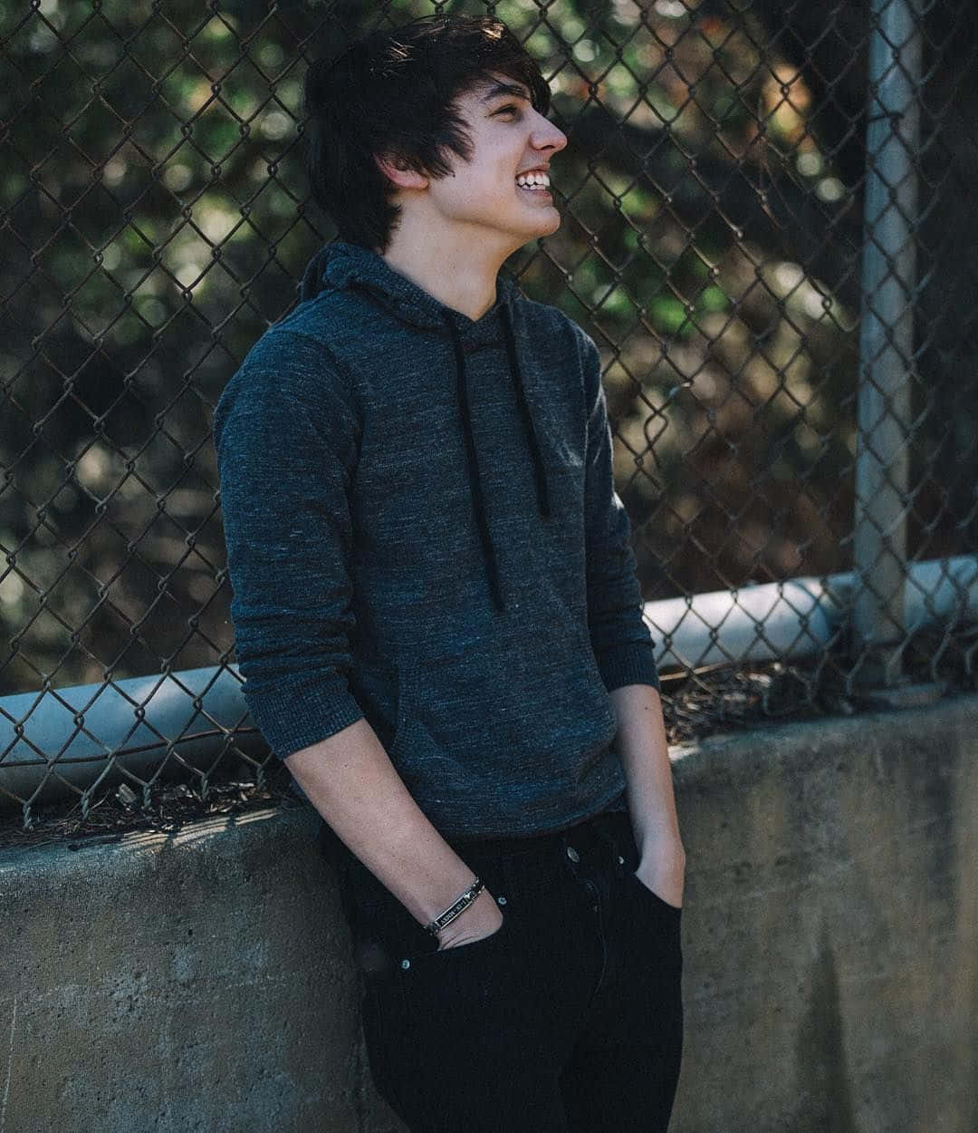 A Young Man Leaning Against A Fence Wallpaper