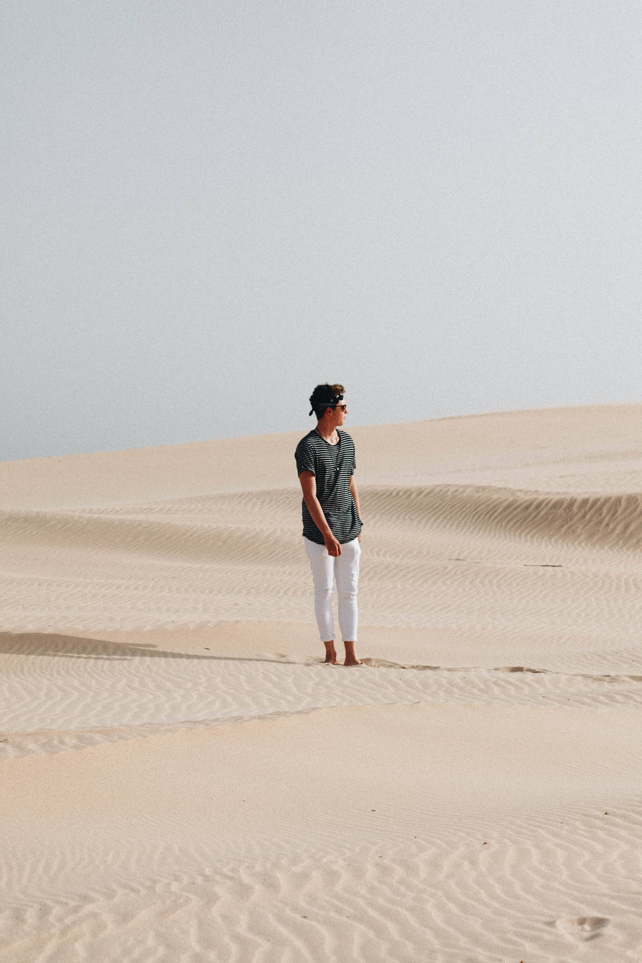 A Youthful Explorer Journeys Through A Desert Landscape Wallpaper