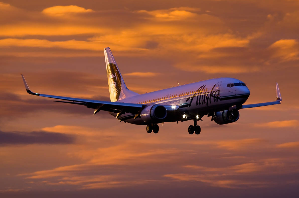 Alaska Airlines Flying On Orange Dusk Skies Wallpaper