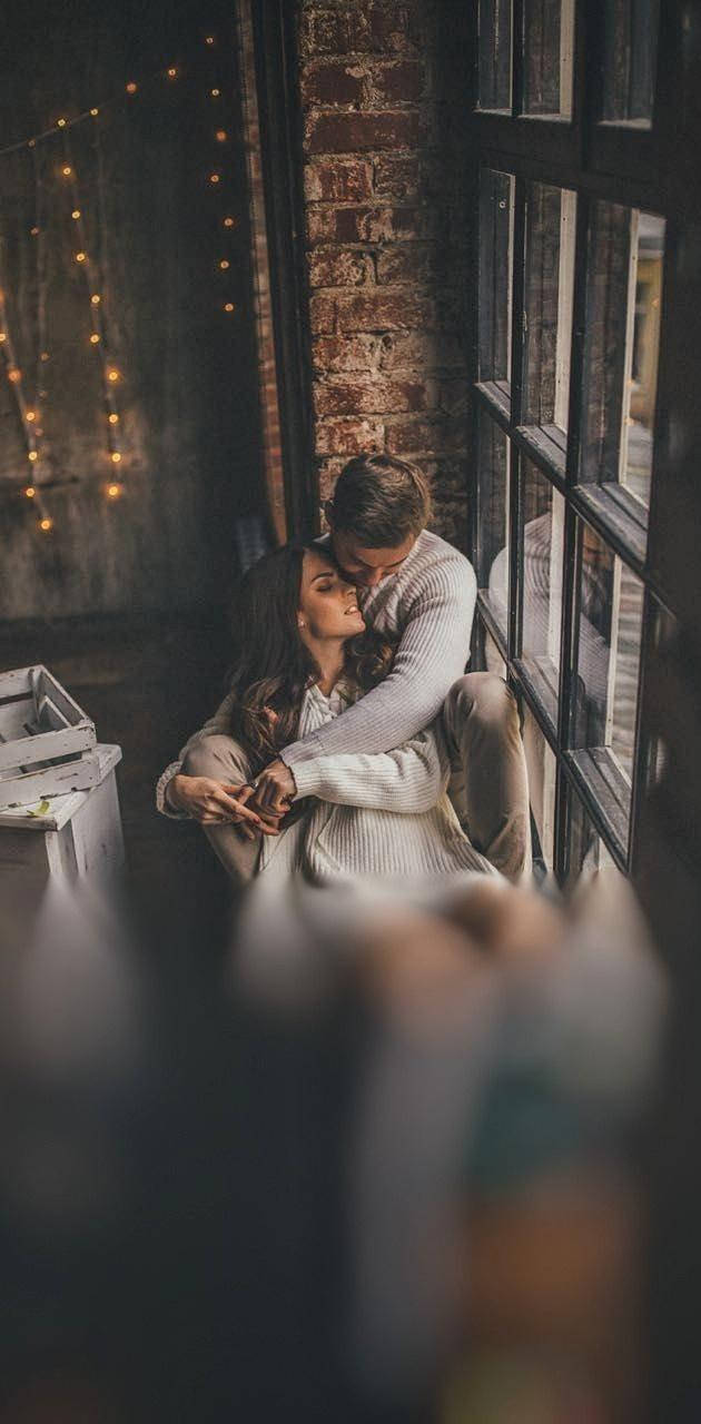 Boyfriend And Girlfriend Cuddling By The Window Wallpaper