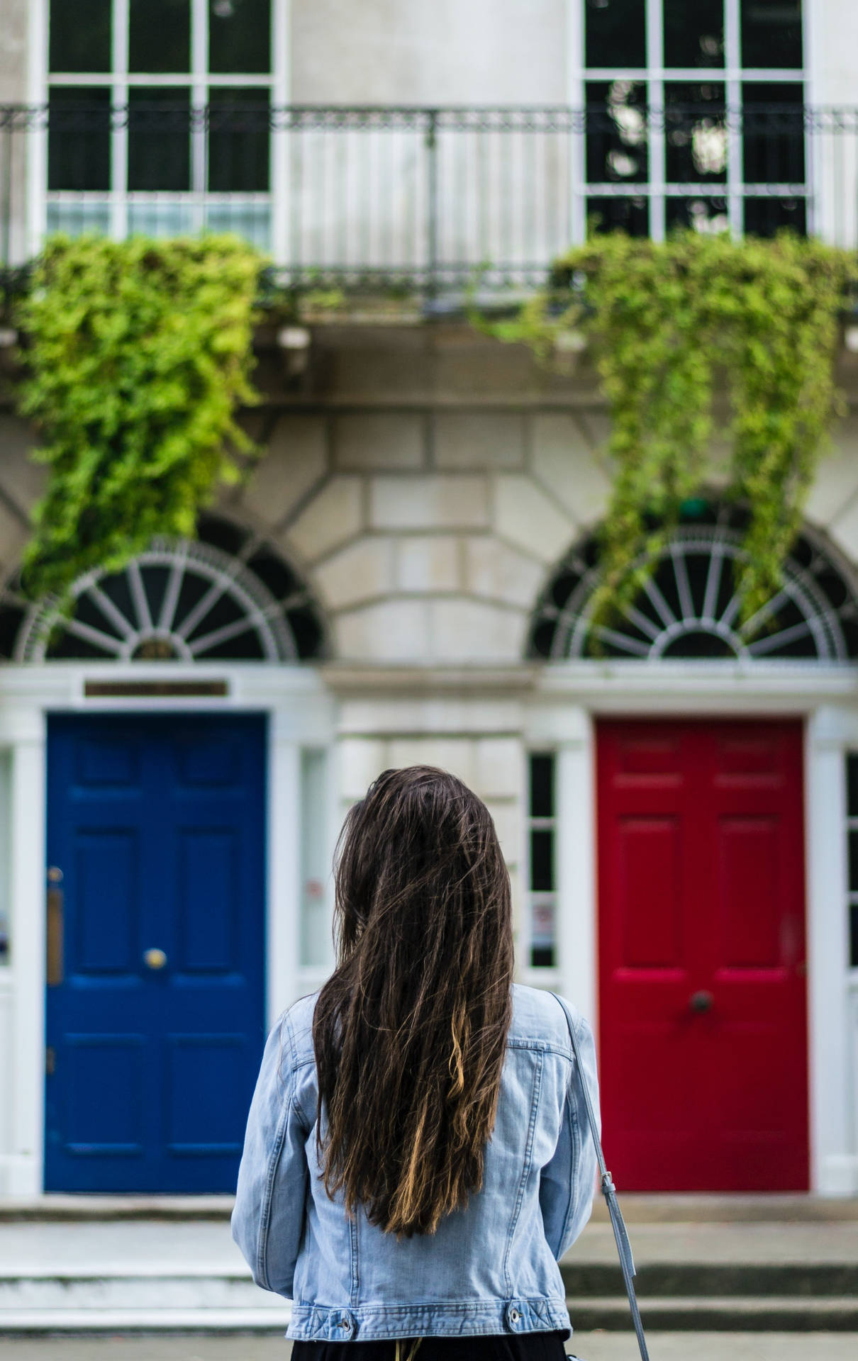 Caption: Elegantly Dressed Woman Posing Between Twin Doors Wallpaper