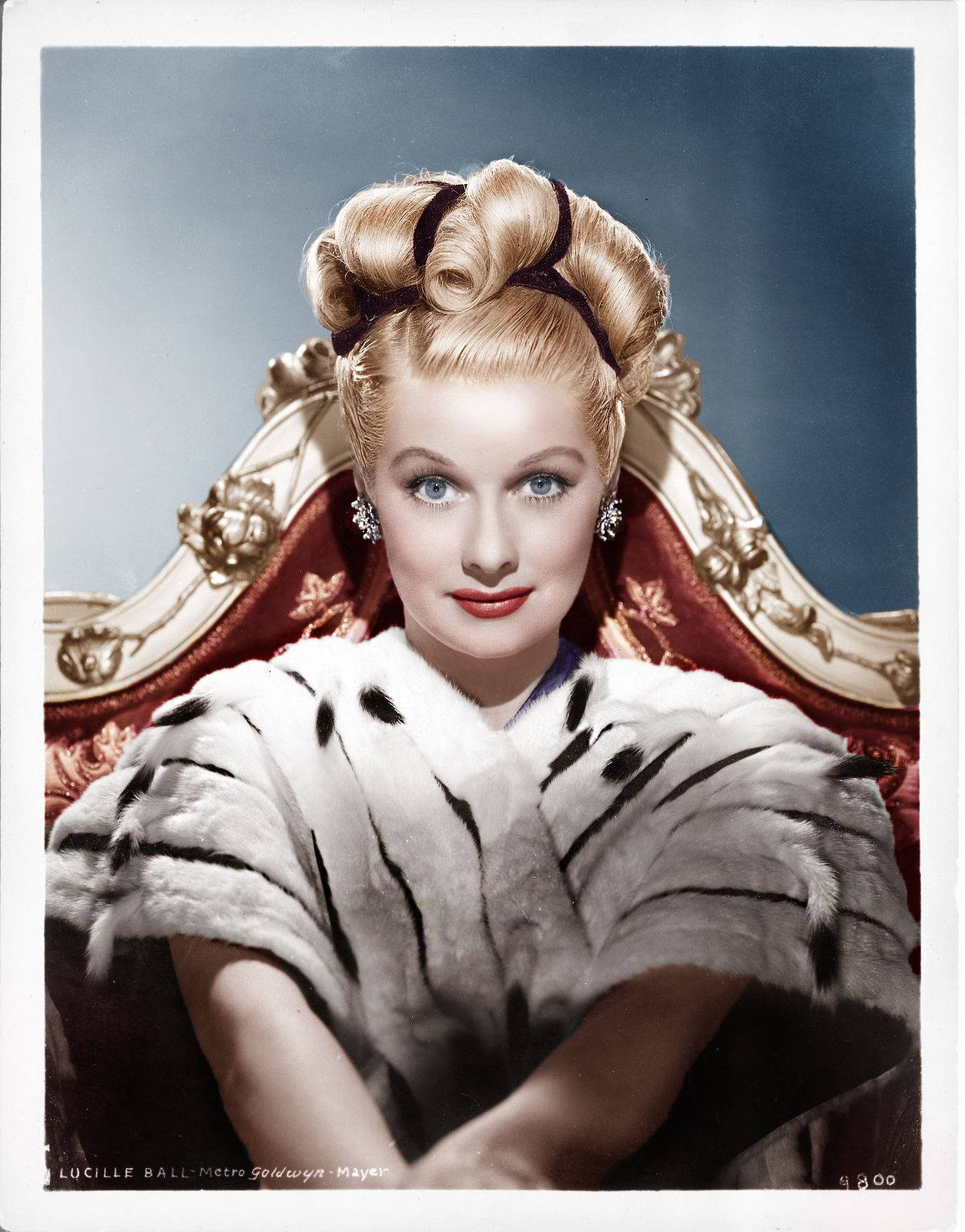 Caption: Lucille Ball Elegantly Sitting On A Red Chair Wallpaper