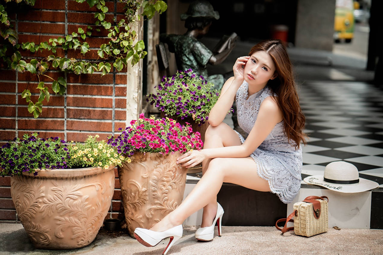 Captivating Asian Woman Posing Near Floral Display Wallpaper