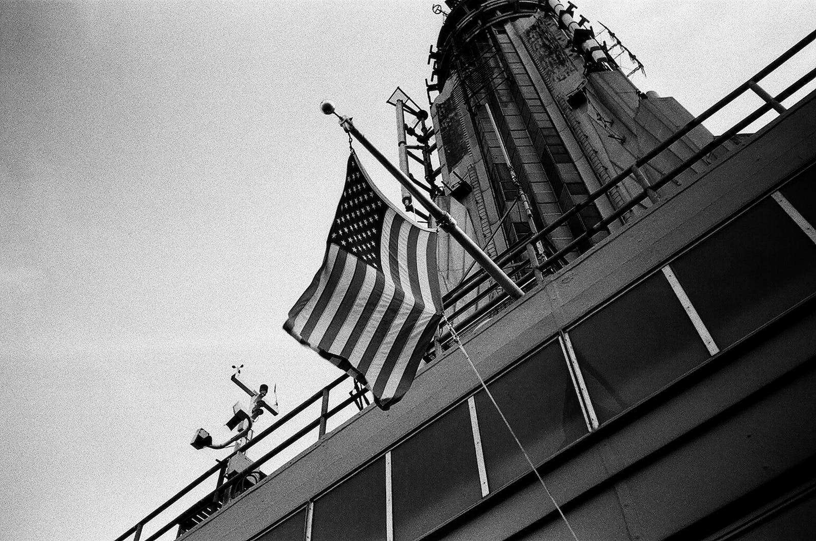 Dark American Flag Hanging In Front Of A Building Wallpaper