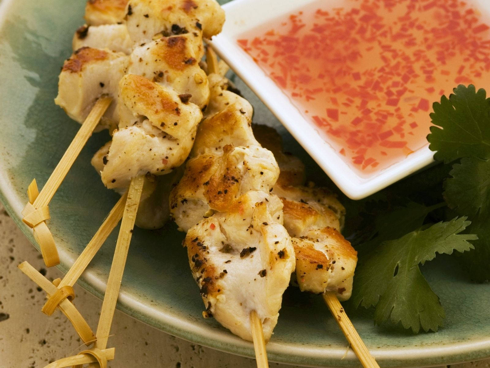 Delicious And Savory Satay Dish Served With Spicy Chili Sauce And Fresh Coriander Leaves Wallpaper