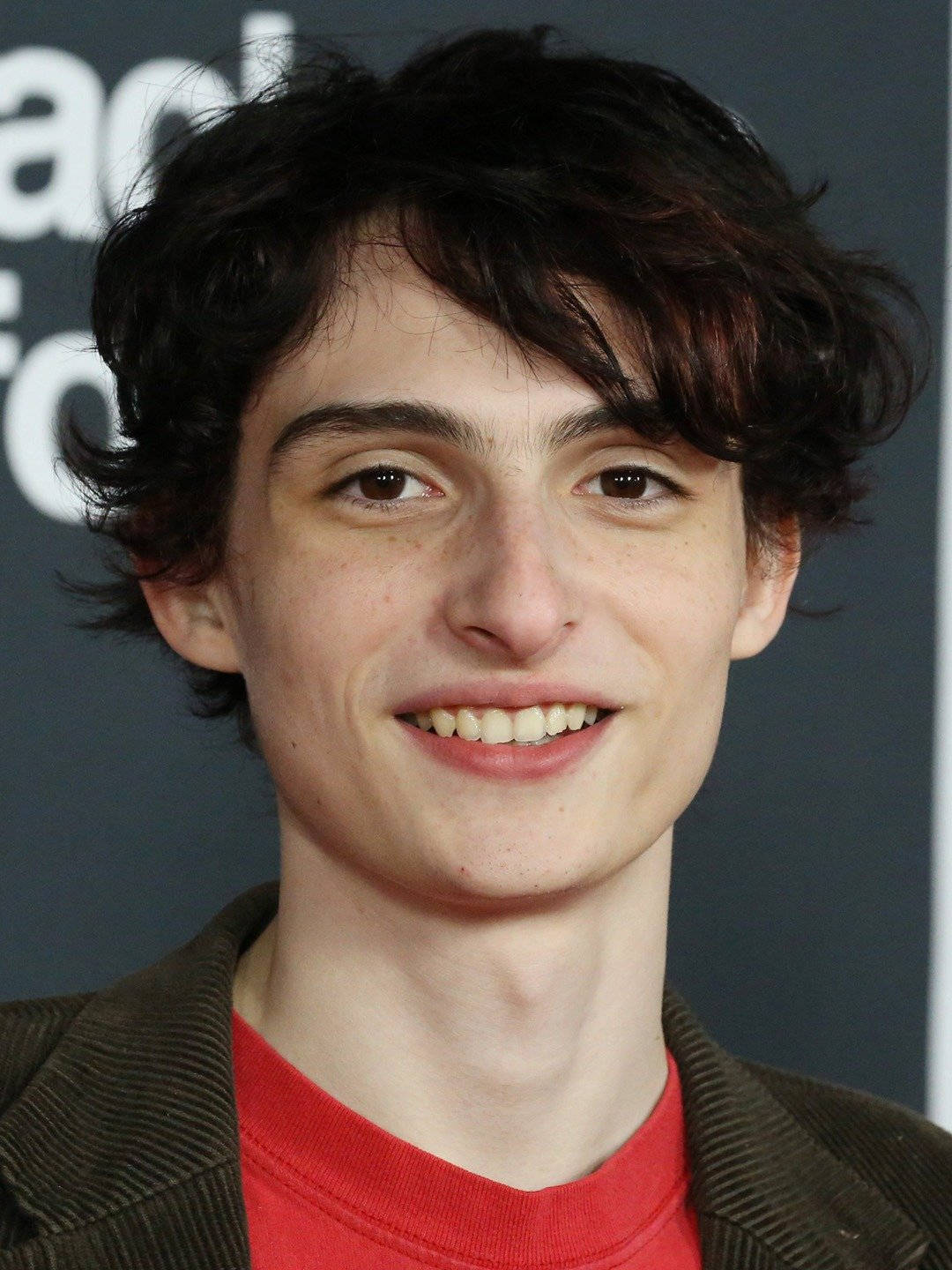 Finn Wolfhard Smiling On Red Carpet Wallpaper