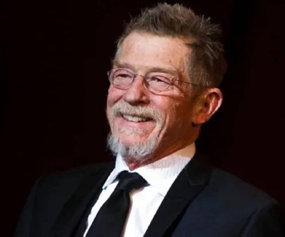 John Hurt Smiling Suit And Glasses Wallpaper