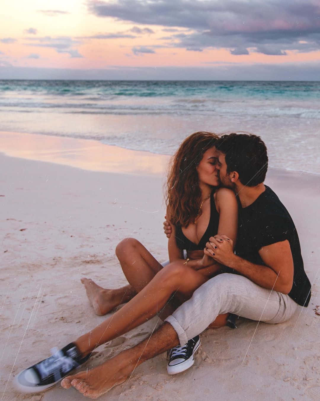 Love Unleashed: A Blissful Couple Enjoying The Beach Sunrise Wallpaper