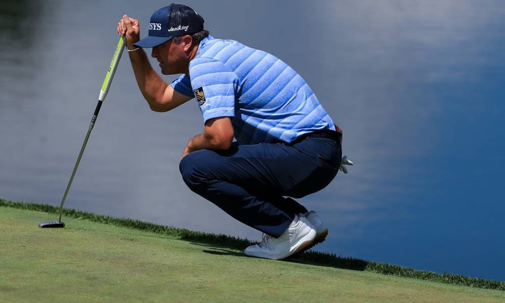 Ryan Palmer Squatting Beside Lake Wallpaper