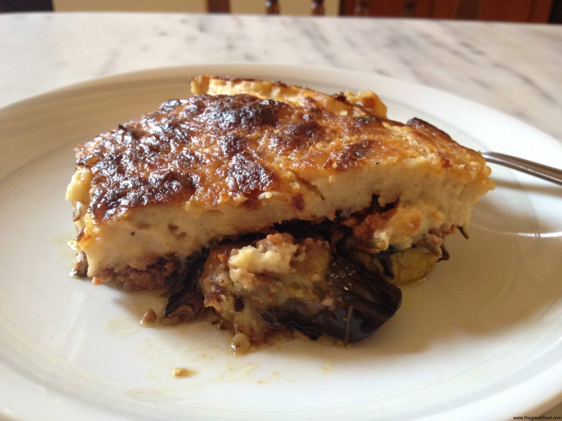 Slice Of Baked Moussaka On A White Ceramic Wallpaper