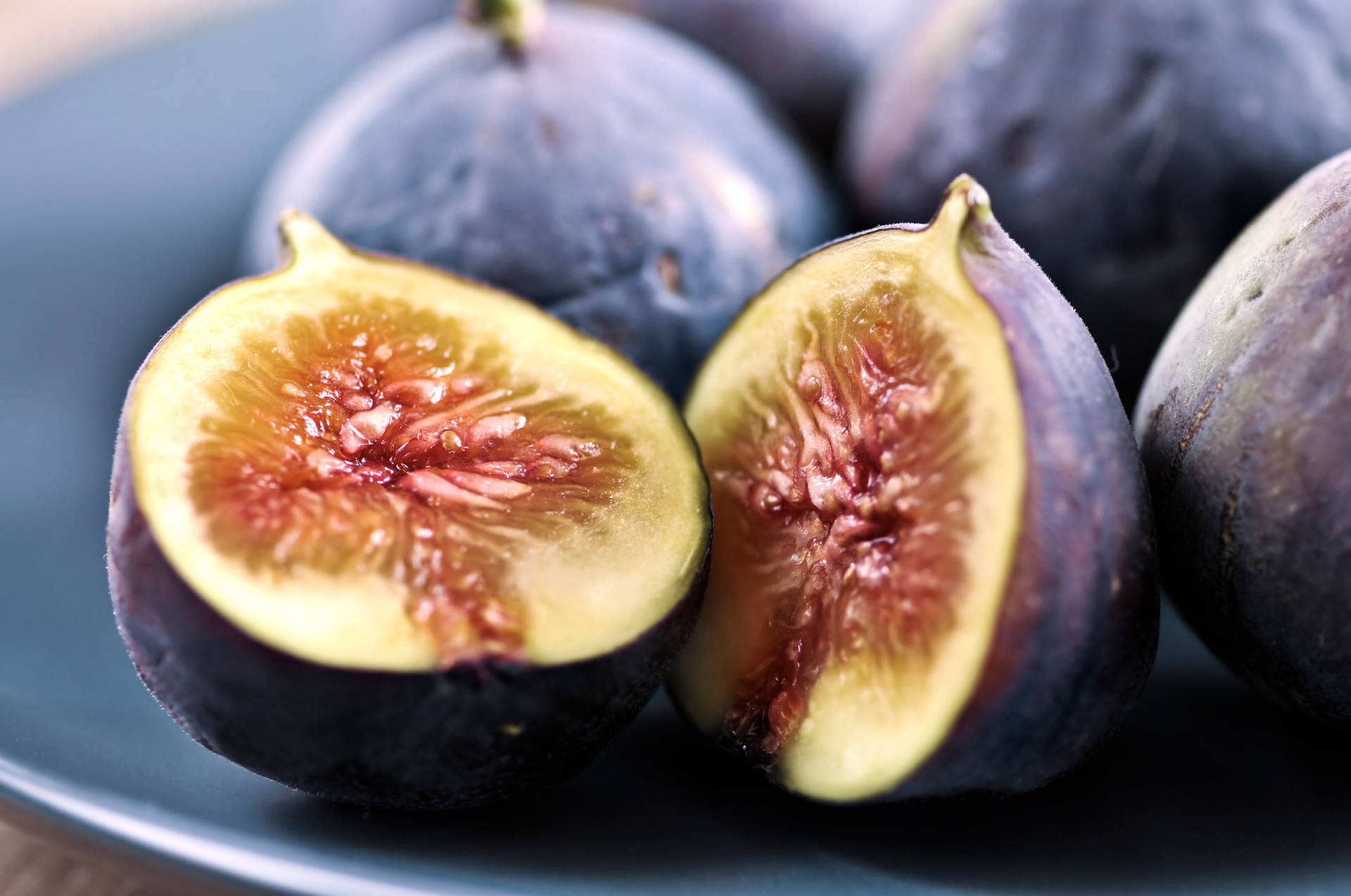 Sliced Figs Adorning A Blue Plate Wallpaper