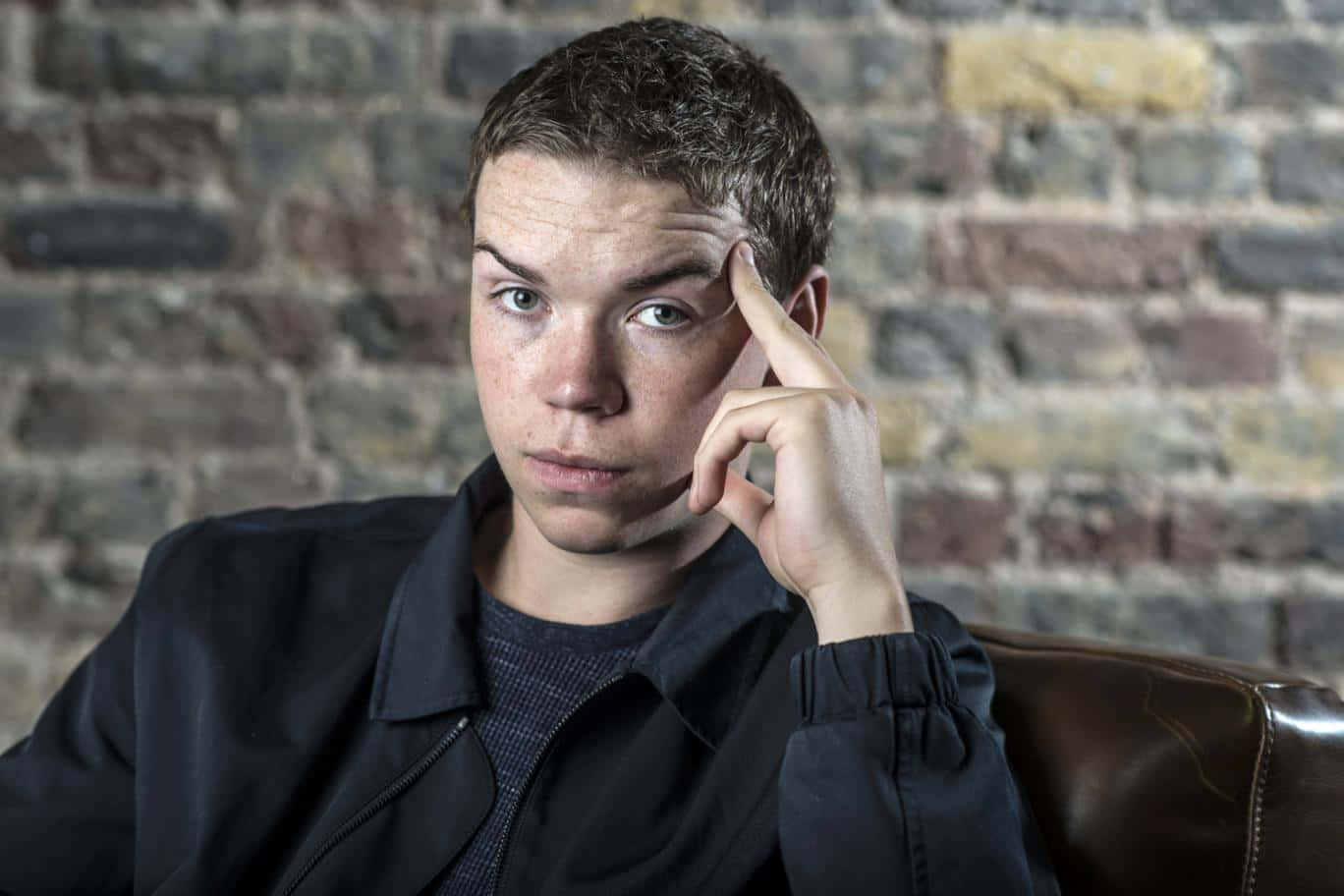 Thoughtful Man Seated Against Brick Wall Wallpaper