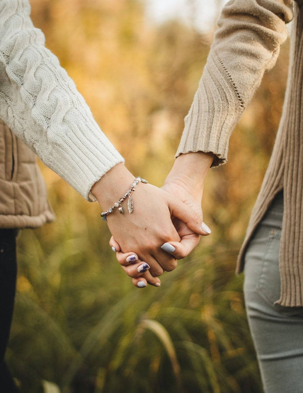 Two Girls In Coats Holding Hands Wallpaper