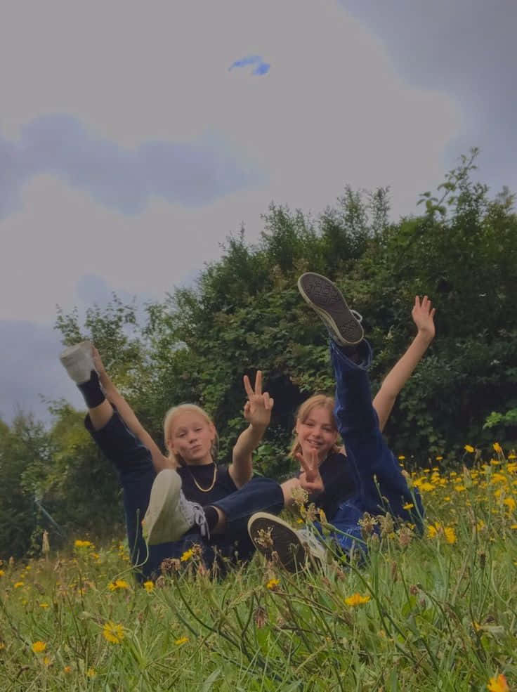 Two Girls Laying In A Field Wallpaper