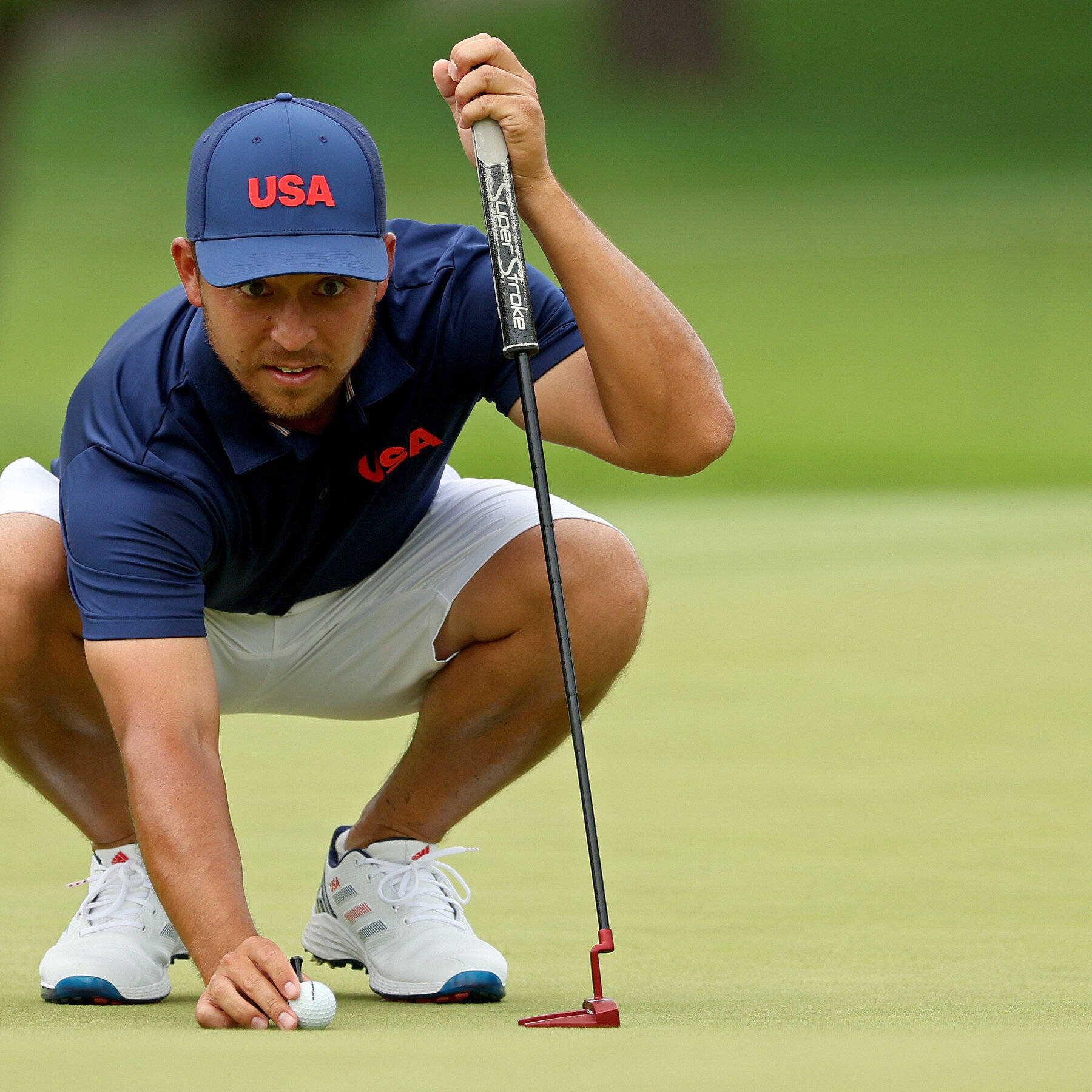 Xander Schauffele Crouching On Golf Course Wallpaper