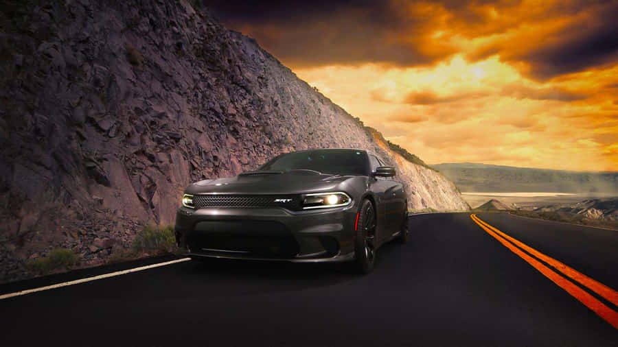 A Black Car Driving Down A Road With A Mountain In The Background Wallpaper