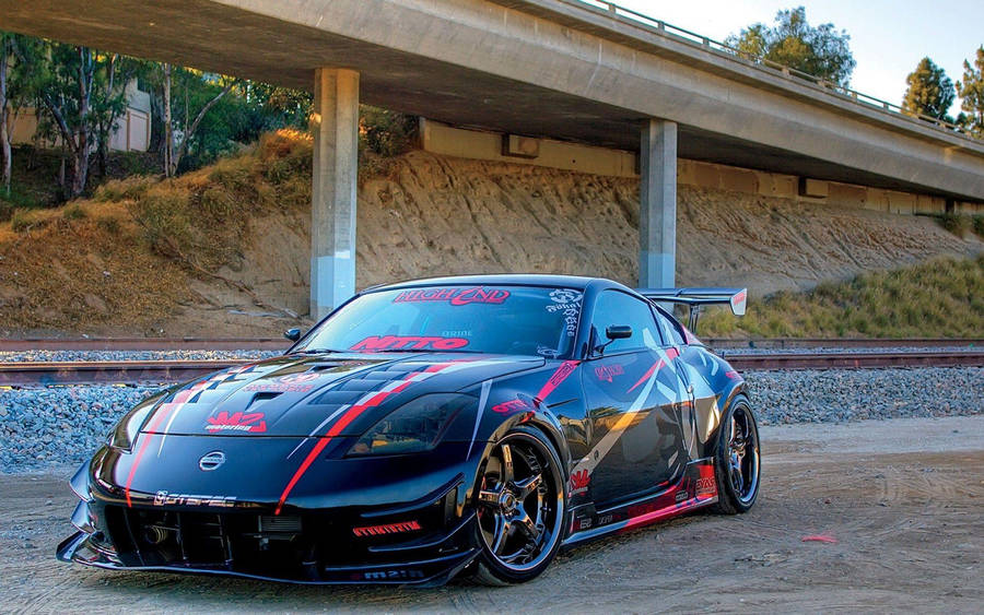 A Black Sports Car Parked Under A Bridge Wallpaper