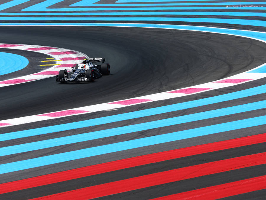 A Car Driving Down A Track With A Blue And Red Stripe Wallpaper