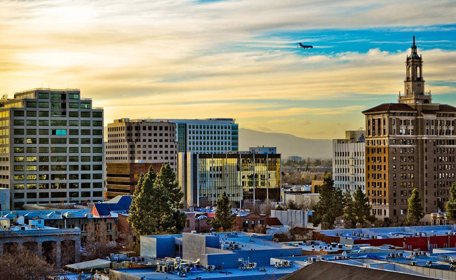 A City Skyline With A Plane Flying Over It Wallpaper