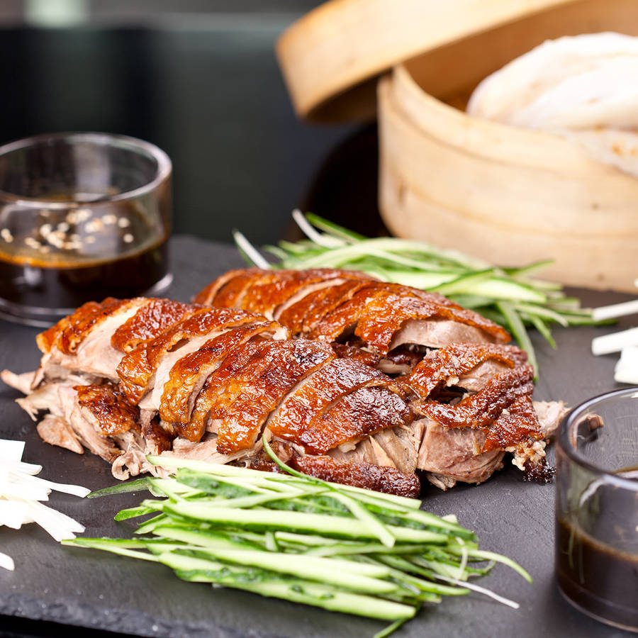 A Delectable Feast: Crispy Glazed Roasted Peking Duck Served With Vibrant Green Beans Wallpaper