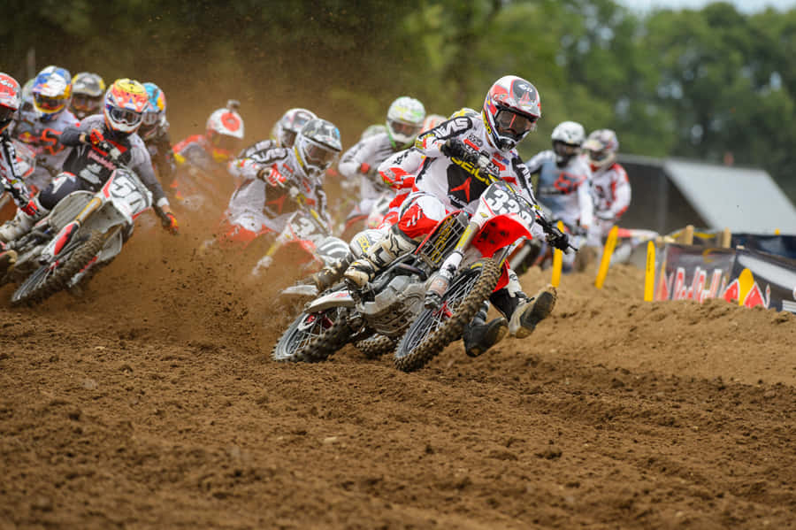 A Group Of Dirt Bikers Racing On A Dirt Track Wallpaper