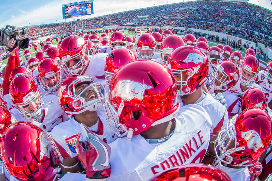 A Group Of Football Players Huddle Together Wallpaper