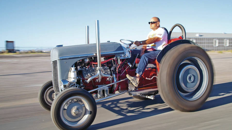 A Hardworking Farmer Driving A Ford N-series Tractor Wallpaper