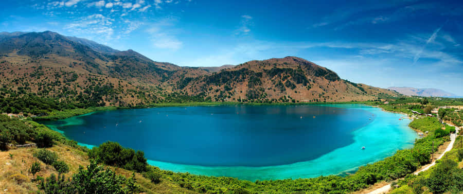 A Majestic Mountain Lake Fills Up The Horizon On A Sunny Day. Wallpaper