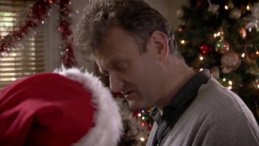 A Man And Woman Kissing In Front Of A Christmas Tree Wallpaper