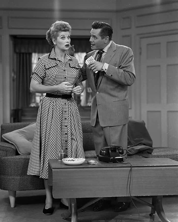 A Man And Woman Standing In Front Of A Couch Wallpaper