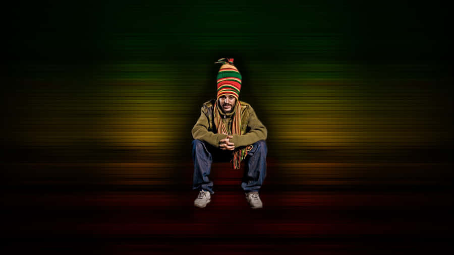 A Man In A Hat Sitting On The Ground Wallpaper