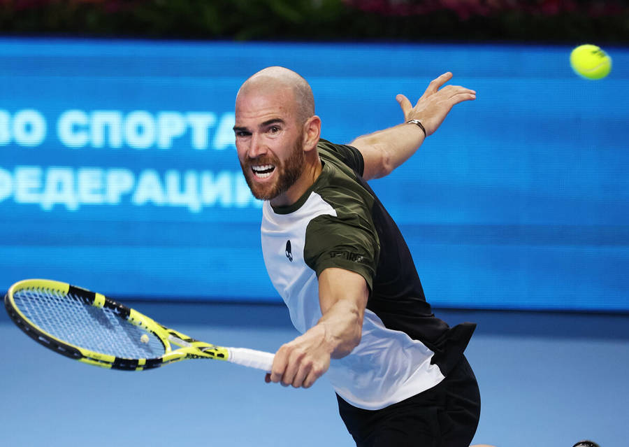 A Man Is Hitting A Tennis Ball With His Racket Wallpaper