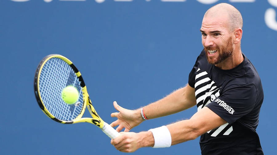 A Man Is Hitting A Tennis Ball With His Racket Wallpaper