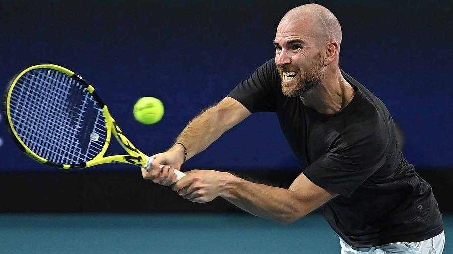 A Man Is Hitting A Tennis Ball With His Racket Wallpaper