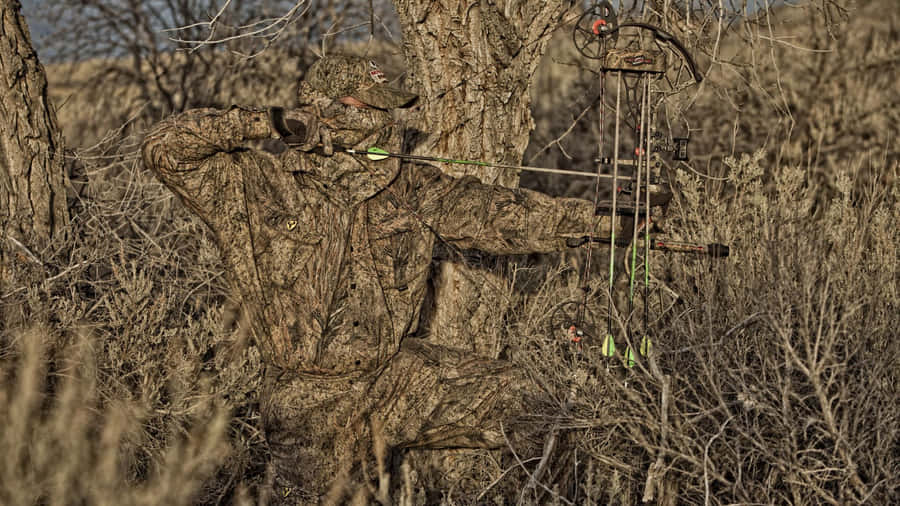 A Man Is Standing In The Grass With A Bow Wallpaper