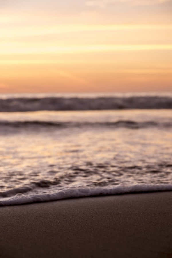 A Man Is Standing On The Beach At Sunset Wallpaper