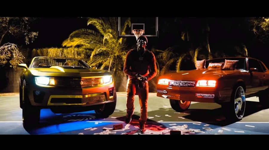 A Man Standing Next To Two Cars With Lights On Wallpaper