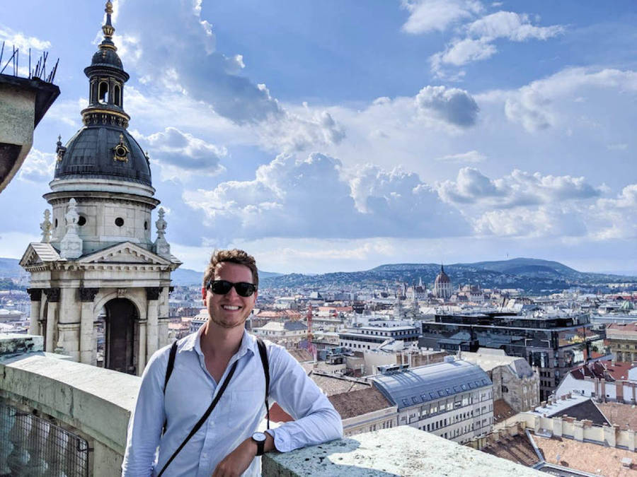 A Man Standing On A Rooftop Overlooking A City Wallpaper