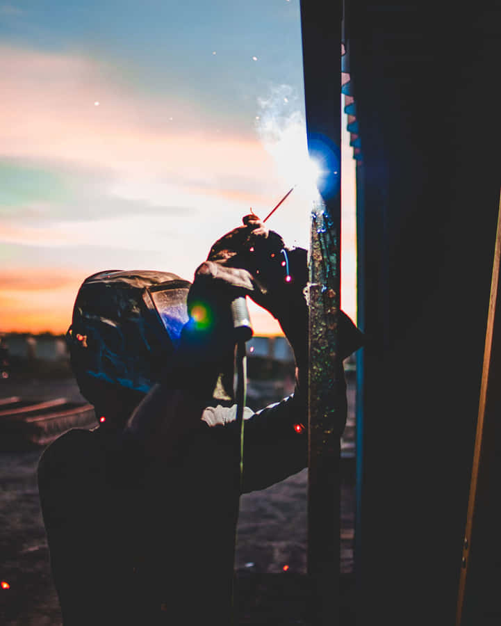 A Man Welding At Sunset Wallpaper