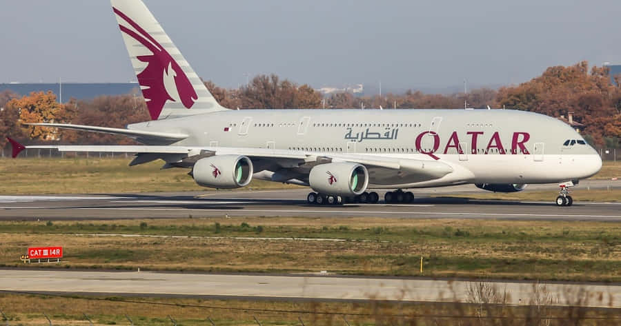 A Qatar Airways Airplane Is Taking Off From An Airport Wallpaper