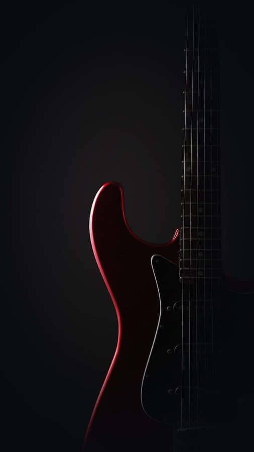 A Red Electric Guitar Is Shown Against A Black Background Wallpaper