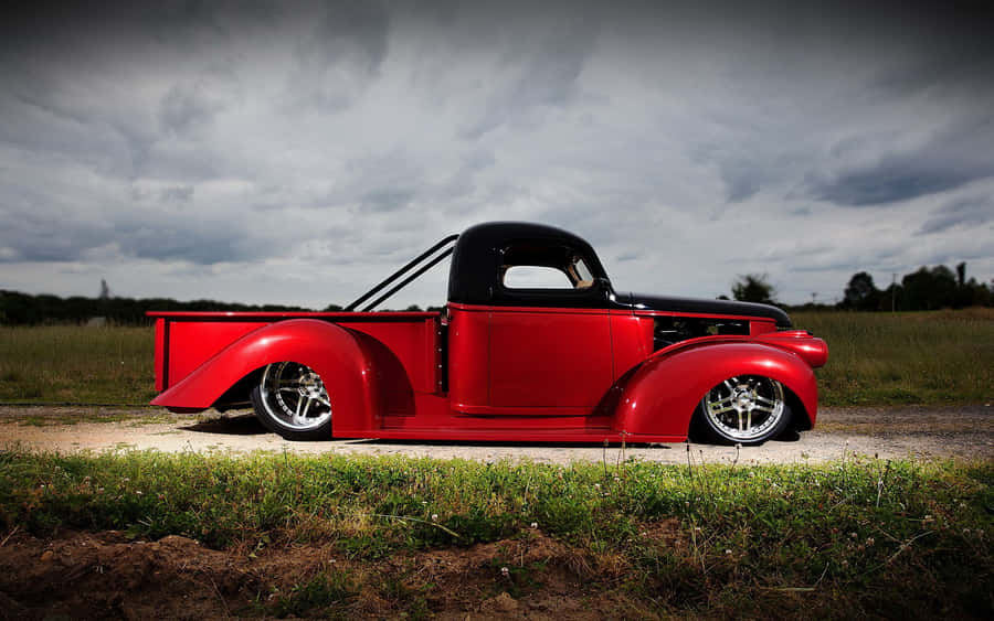 A Red Truck Parked On A Dirt Road Wallpaper