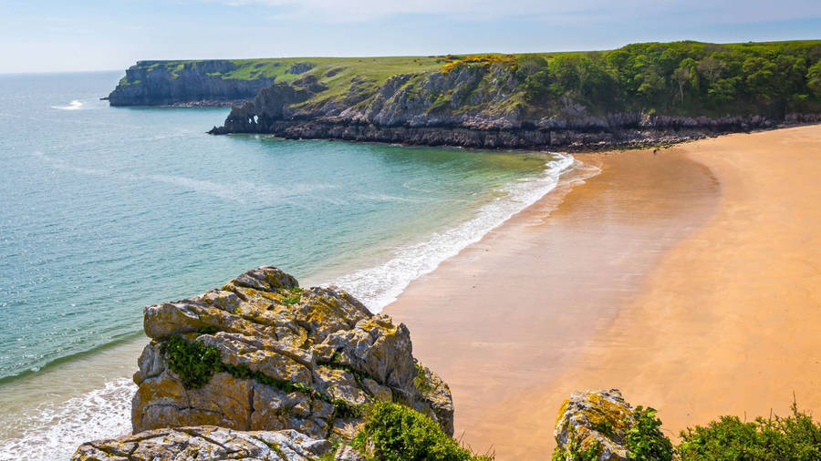 A Sandy Beach With A Cliff And Ocean Wallpaper