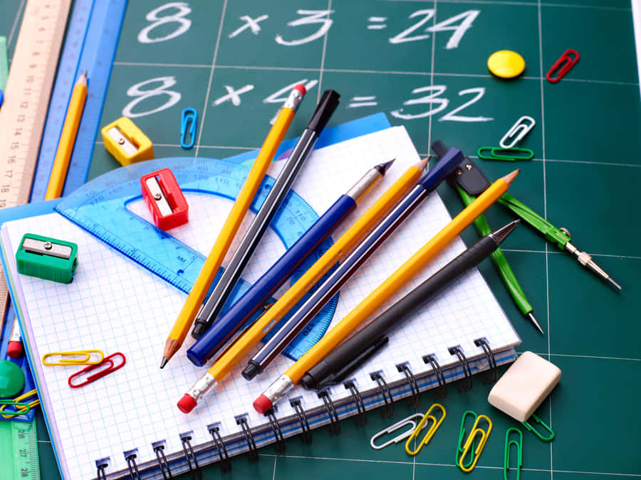 A School Desk With Pencils, Pens, And Other School Supplies Wallpaper