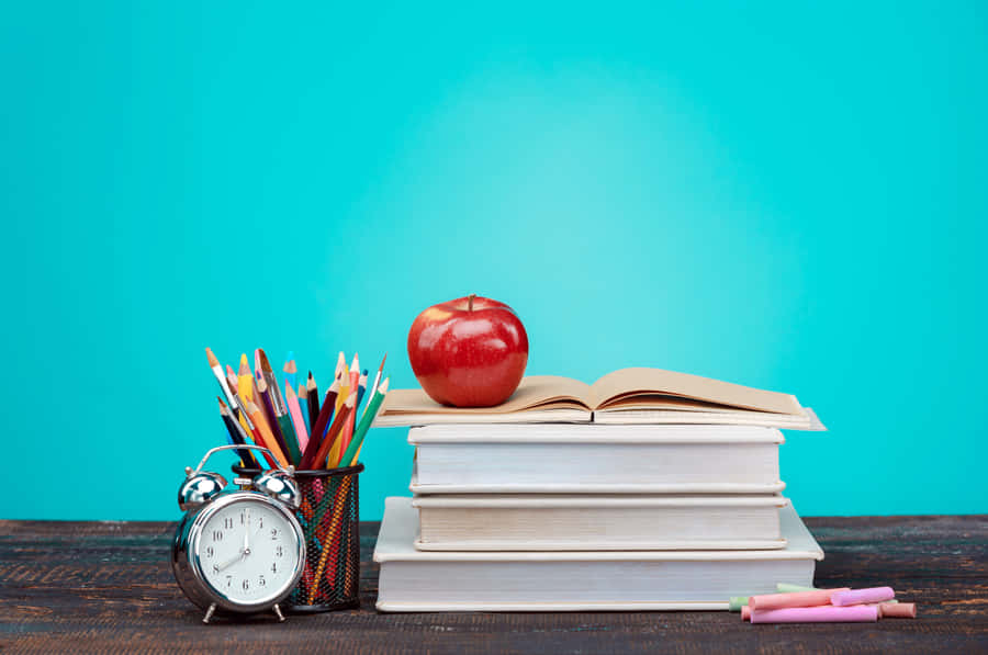 A Stack Of Books With An Apple And Pencils On Top Wallpaper